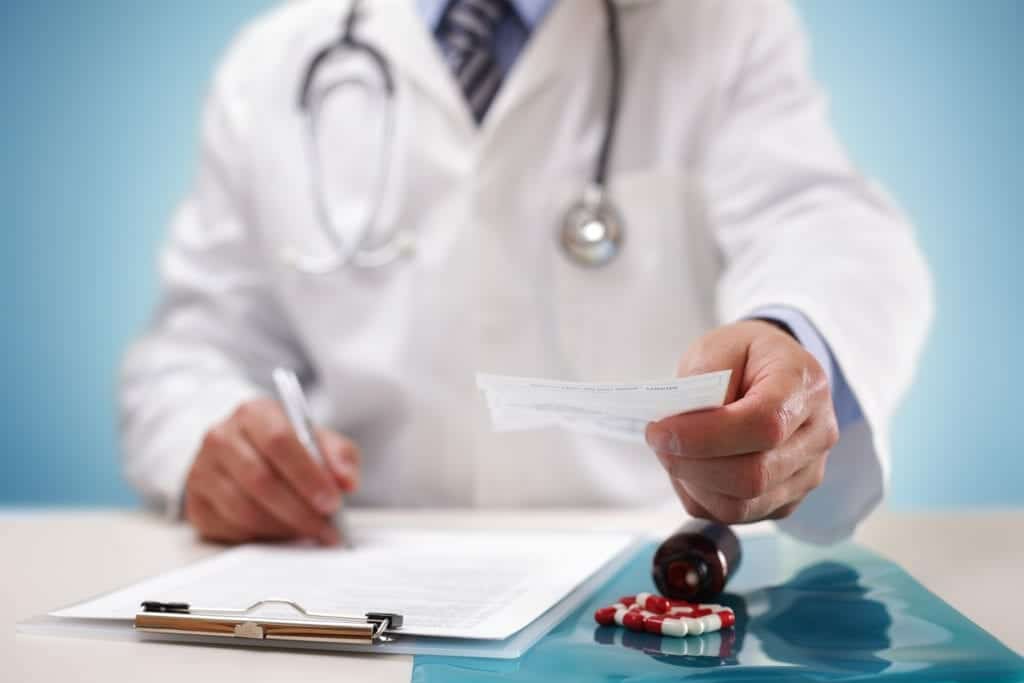 Doctor writes prescription for painkiller and passes it to patient.